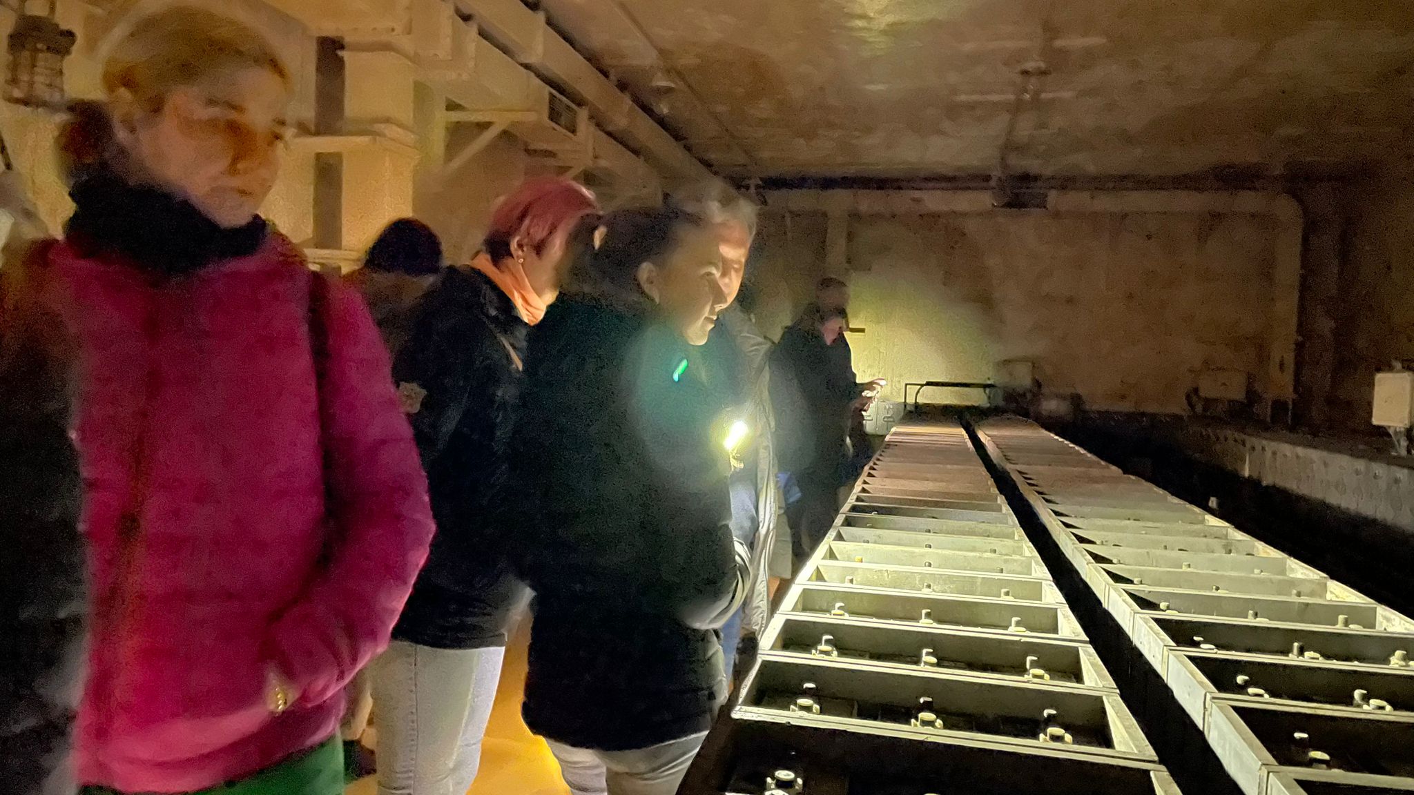 Lidé při temné prohlídce v baterkárně, pouze za svitu baterek